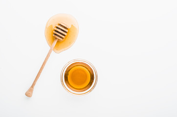 Wooden honey dipper with honey in glass bowl