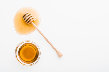 Wooden honey dipper with honey in glass bowl