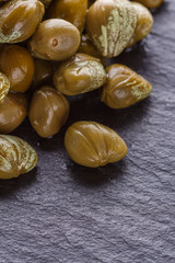 pickled capers on a dark stone background