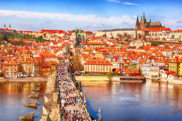 Fototapeta premium View of Charles Bridge, Prague Castle and Vltava river in Prague, Czech Republic from above. Nice sunny summer day with blue sky and clouds. Famous landmarks in Europe.