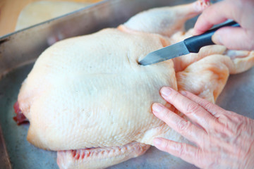 A woman pierces a duck’s skin to allow excess fat to drain during roasting