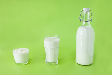 Milk kefir and sour cream are in a row on a green background. Fresh dairy products for breakfast