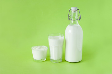 Milk kefir and sour cream are in a row on a green background. Fresh dairy products for breakfast