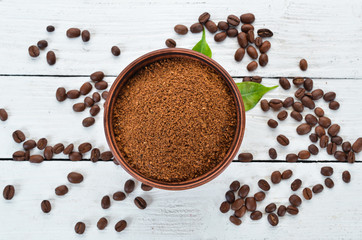 Ground coffee and coffee beans. On a white wooden background. Top view. Free space for your text.