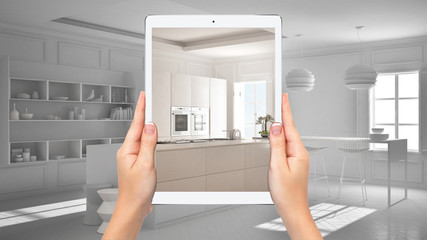 Hands holding tablet showing modern white and wooden kitchen, total blank project background, augmented reality concept, application to simulate furniture and interior design products