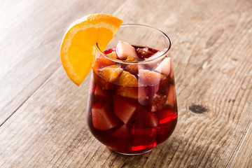 Red wine sangria in glass on wooden table. 