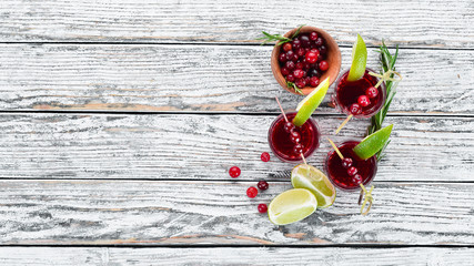 Alcoholic liqueur from a cranberry in a glass. Cranberry, lime, rosemary. On a rustic background. Top view. Free space for your text.