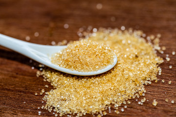 Spoons with brown sugar on wooden.