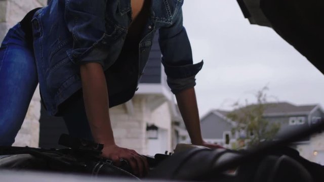 A woman checking under the hood of a diesel vehicle, 23.98 fps.