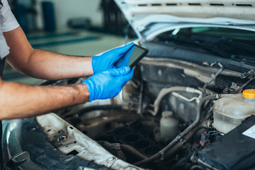 closeup of repairman using tablet in car service