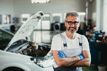 senior worker crossed arms in car service