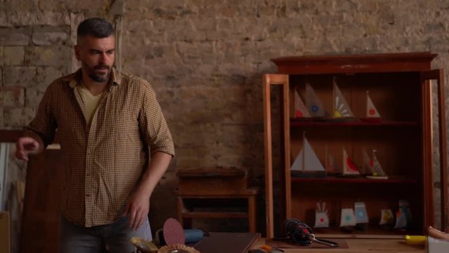 Carpenter in his workshop cleaning the working space