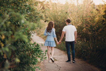 Obraz premium Back view couple walking away in the field, view of couple holding hands, lovers walking holding hands