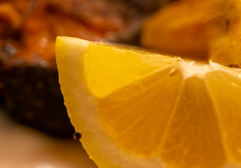 Close-up of a fresh yellow lemon quarter in front of a blurred background with an unrecognizable...