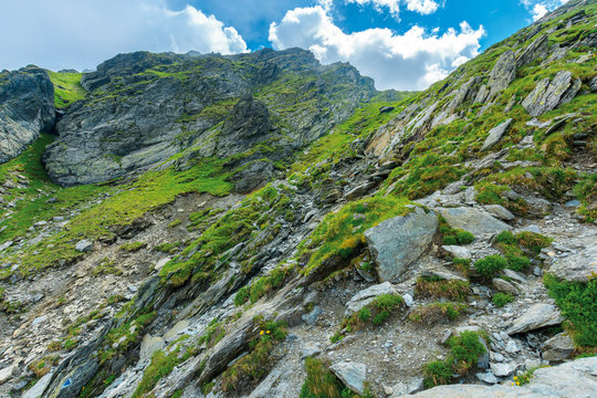 hiking uphill rocky slopes of fagaras mountains. hard path among big and sharp boulders. sunny summer weather with cloudy sky
