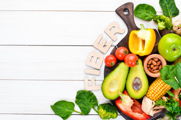 Foods containing natural fiber: avocados, kiwi, apple, tomatoes, spinach, paprika, orange, lemon. Top view. Free space for your text. On a white background.