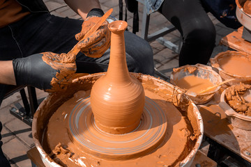 Street potter makes a vase of clay on a potter's wheel. Close-up
