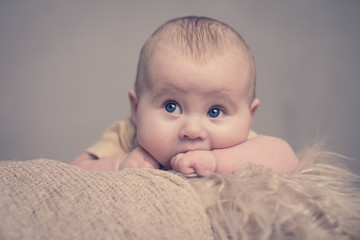Portrait Baby offene Augen mit Hand im Mund schaut in Kamera soft tones