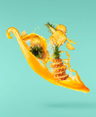 Flying in air fresh ripe whole and cut baby Pineapple with slices and leaves