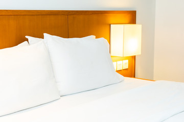 White comfortable pillow on bed with light lamp decoration in bedroom