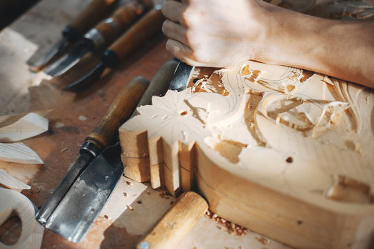 A man carves a tree. The carpenter works with jigsaw in a studio. An engineer provides a tree shape