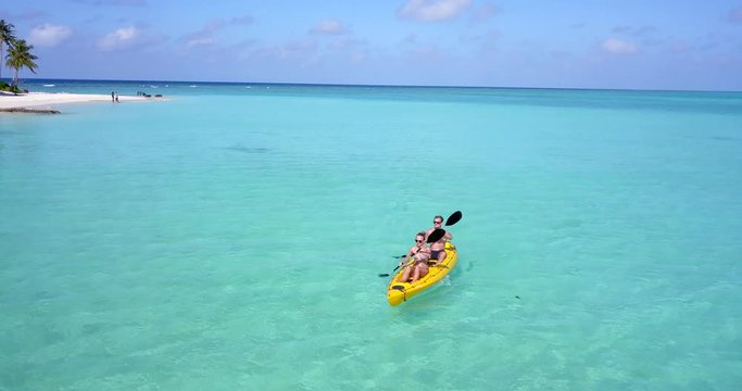 Man and woman couple paddle canoe over beautiful Hawaiian waters on tropical vacation 4k