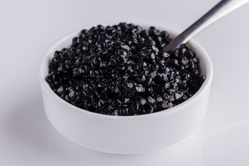 black caviar in a bowl on a white acrylic background