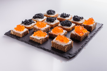 Snack with red and black caviar on a stone plate