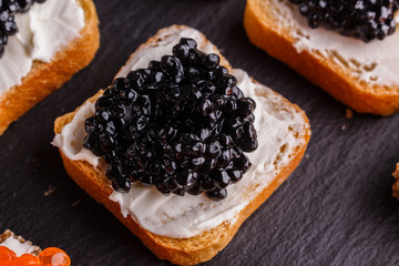 Snack with red and black caviar on a stone plate