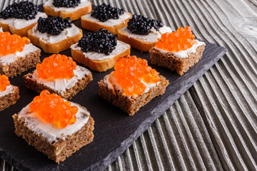 Snack with red and black caviar on a stone plate