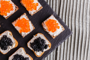 Snack with red and black caviar on a stone plate