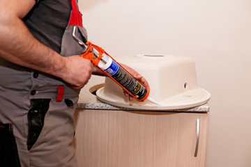 A handyman installing  kitchen artificial stone sink in a wooden cabinet covered with countertop...