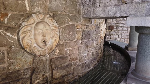 Selvino, Bergamo, Italy. Water spurting from the fountain with a marble mask in the center of the village. Selvino is a mountain resort
