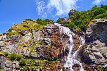 Rocky waterfall in summer mountain