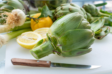 Preparation of heads of fresh raw artichokes plants from artichoke plantation in Argolida, Greece ready to cook with lemon