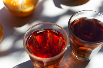 Young rose wine served outside in garden on white table with fresh orange in sun lights