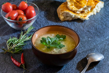 Light soup in chicken broth, with noodles and spices on a dark background. Horizontal orientation