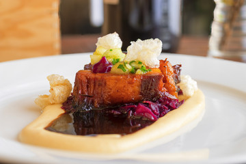 Main course, dish with roasted pork belly, red sauerkraut and mashed potatoes. Demonstration cooking.