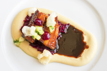 Main course, dish with roasted pork belly, red sauerkraut and mashed potatoes. Demonstration cooking. Top view.