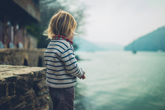 Little toddler by river outside boathouse