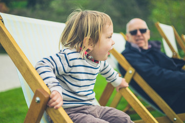 Toddler and grandfather sitting in deck chairs