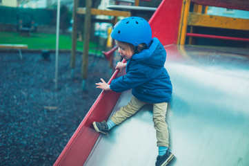 Toddler wearing helmet on slide