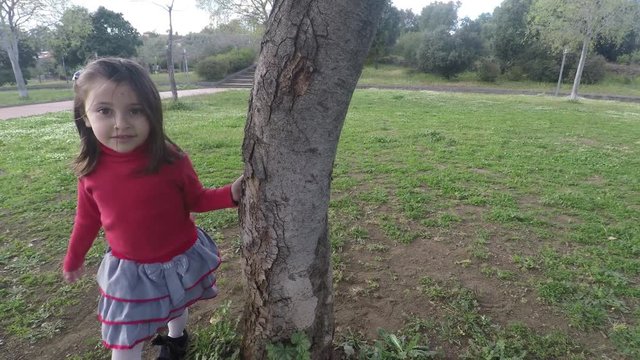 4k Little girl in nature at park playing happy turning a tree, beautiful child girl in nature having fun