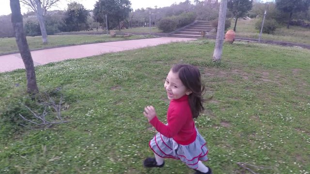 4k Little girl running happy on grass at park, adorable cheerful child girl enjoying spring