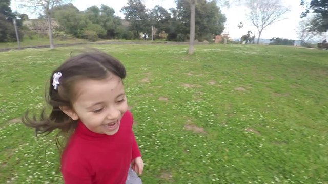 4k Little girl running happy on grass at park, beautiful cheerful child girl enjoying spring