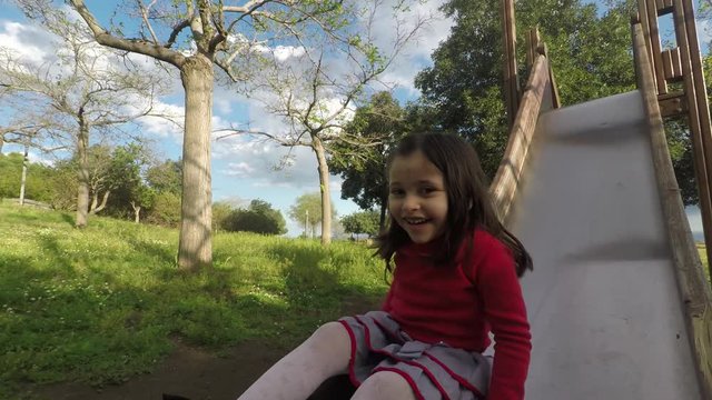 4k Little cute girl playing at park in spring, cheerful child girl smiling while enjoying park