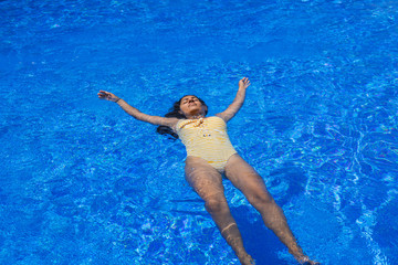young indian woman floating in the pool