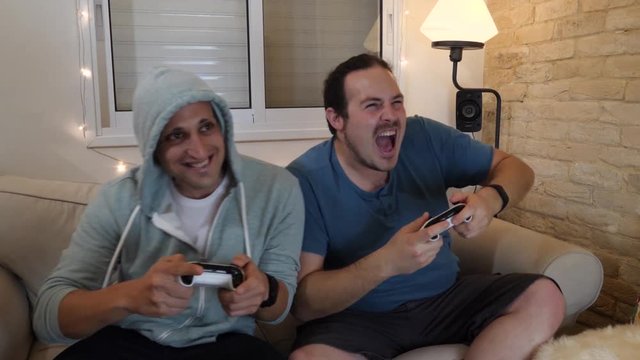 Cheerful friends playing console games on couch