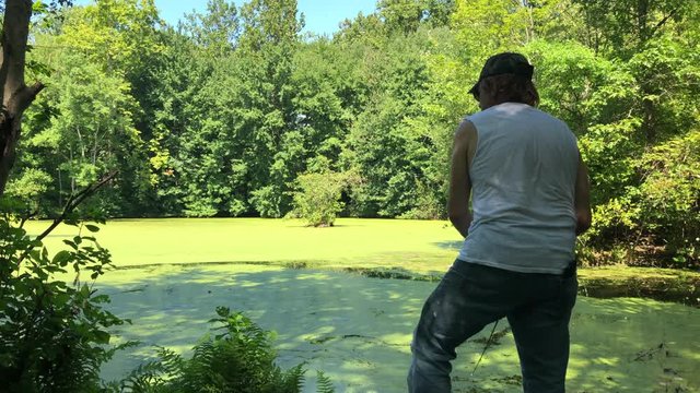 Man Fishing in a pond casting and reeling in