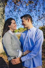 Fototapeta premium Happy young couple smiling and hugging in a forest in the middle of nature on a sunny spring day.